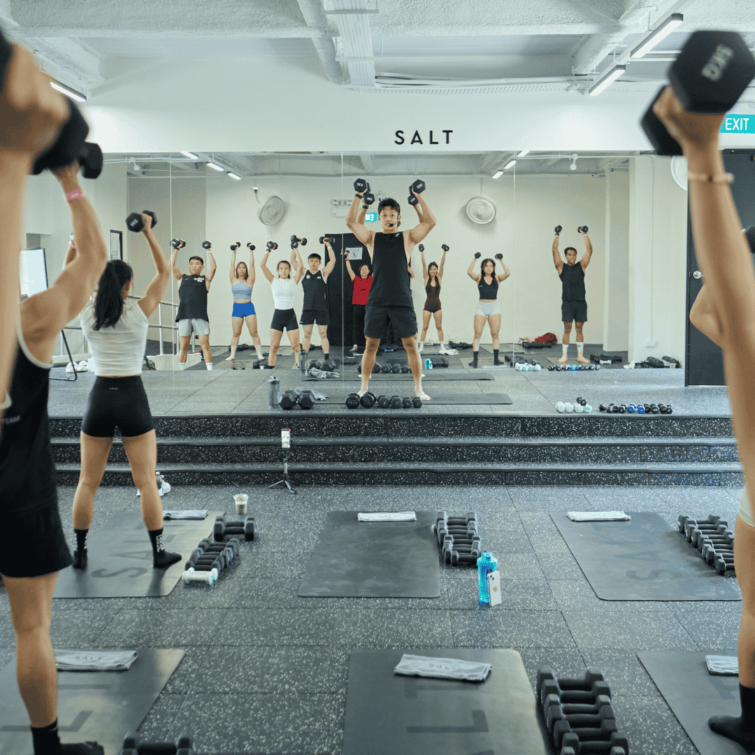 Group strength training class at SALT Fitness Singapore, instructor-led session with dumbbells and rhythmic movement